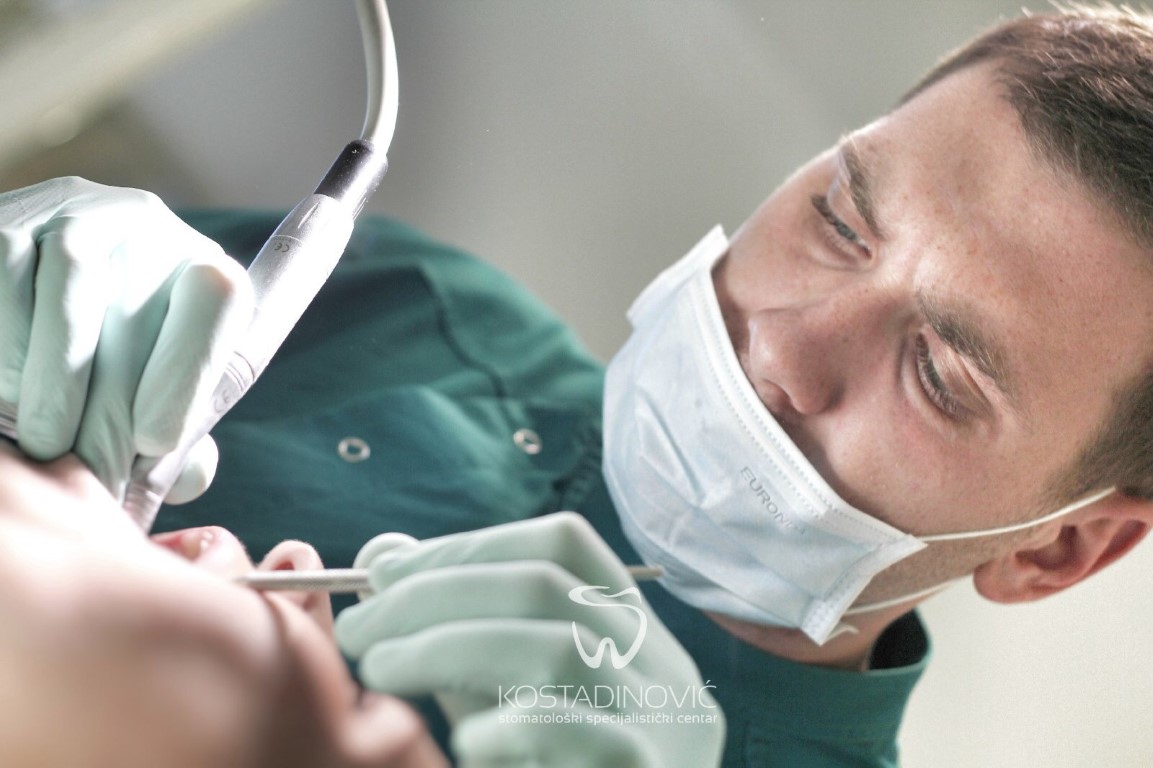 Stomatolog Kostadinovic u precesu pregleda i popravka zuba, u zelenoj uniformi.
