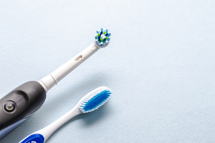 Closeup of Brushing Heads of Professional Electric Toothbrush and Manual Brush on Blue  Background. Horizontal Image